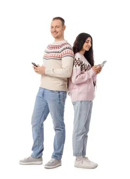 Young couple in warm sweaters using mobile phones on white background Stock Photos