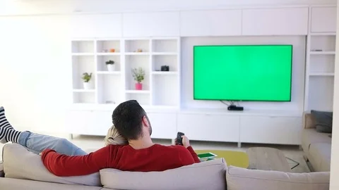 A Young Couple Watches A Tv With A Green Screen In A Cozy Living Room Stock Footage