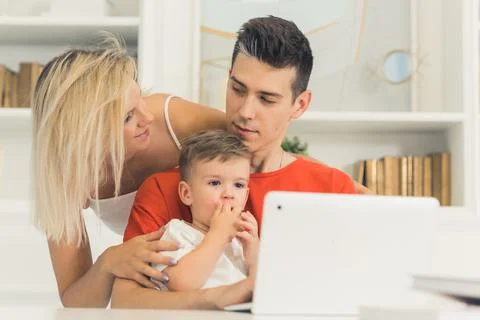 Young couple watching something in the laptop with their little son, medium Stock Photos
