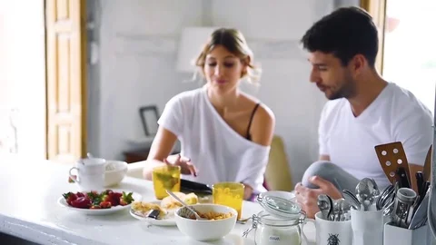 Young couple watching tablet while sitting at table and having breakfast Stock Footage 74727866
