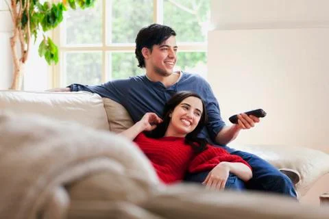 Young couple watching TV on living room sofa Stock Photos