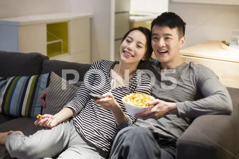 Young Couple Watching Tv On Living Room Sofa