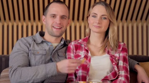 Young Couple Watching TV on the Sofa in the Living Room end eating chips Stock Footage 72474936