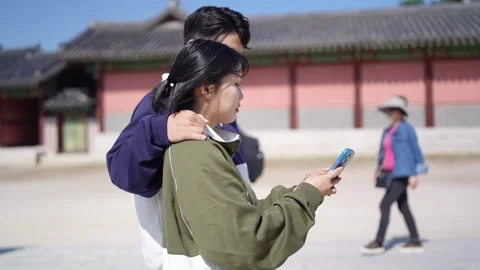 A young couple wearing jerseys is taking a walk in a park with historical 動画素材 292482467