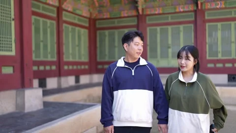 A young couple wearing jerseys is taking a walk in a park with historical Видео 292486472