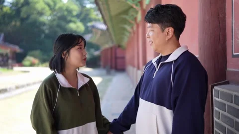 A young couple wearing jerseys is taking a walk in a park with historical 動画素材 292498618