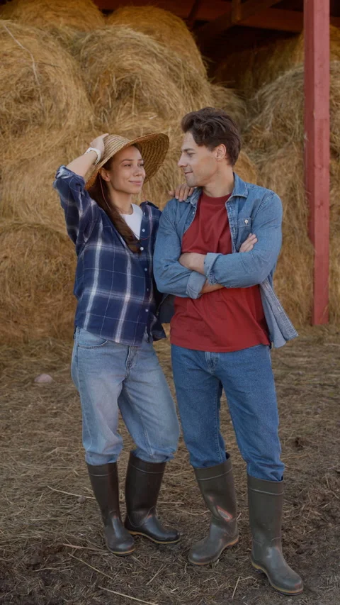 Young Couple Wearing Work Clothes Posing against Hay Sheaves on Farm Stock Footage 318449221