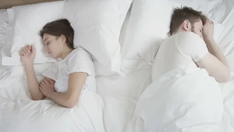 Young couple in white bed laying unhappy after a quarrel Stock Footage 73349189