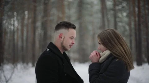 Young couple in the winter forest. Man girl warms his hands with his breath Stock Footage 73042788