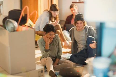 Young couples roommates using laptop unpacking moving boxes in new apartment 写真素材