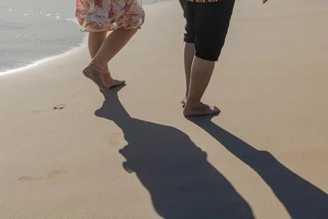 Young couples walking on the side of the beach enjoying vacation Stock Photos