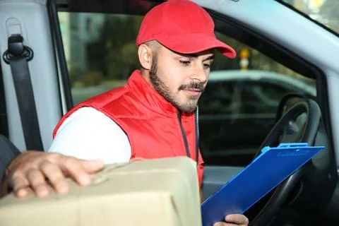 Young courier checking amount of parcels in delivery van Fotos Stock