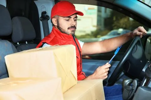 Young courier checking amount of parcels in delivery van Fotos Stock
