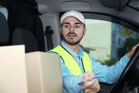 Young courier checking amount of parcels in delivery van Fotos Stock