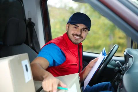Young courier checking amount of parcels in delivery van Fotos Stock