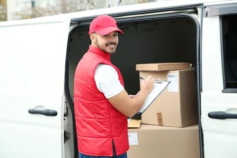 Young courier checking amount of parcels in delivery van, outdoors Stock Photos