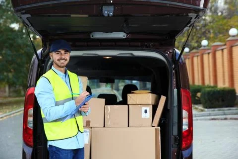 Young courier checking amount of parcels in delivery van, outdoors Fotos Stock