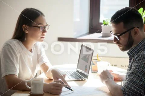 Young coworker looking through papers discussing and negotiating Stock Photos