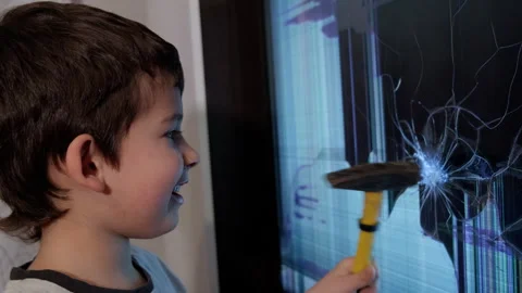 The Young Craftsman: A Curious Boy Fixing a TV Screen with a Hammer Stock Footage 257576033