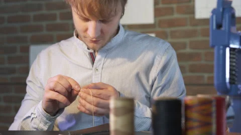 Young craftsman puts in the needle thread to hand sew a DIY product. 스톡 동영상 130214278