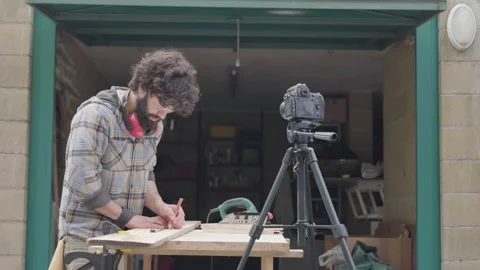 Young craftsman recording video on camera teaching working with wood workshop Vídeos de archivo 152967823