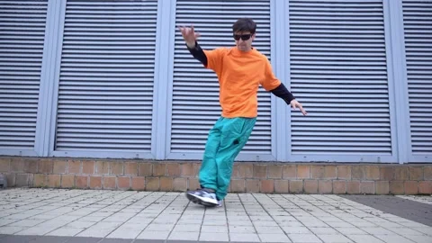 Young crazy guy dances hip hop on city street Stock Footage 293840063