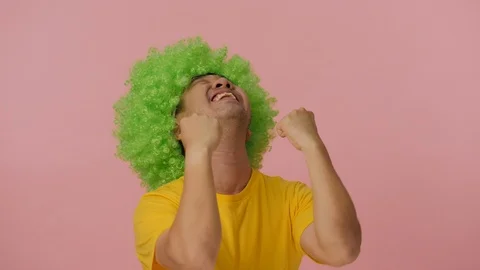 Young crazy man with colored afro wig expressing happiness. Video stock 94521627