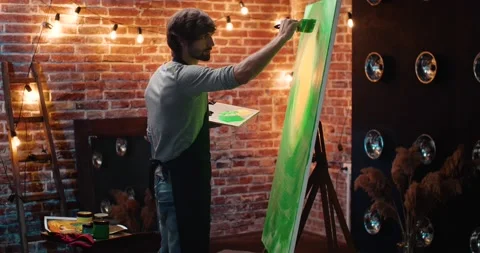Young Creative Artist Painter is creating on Loft Art Studio, Cozy Evening Video stock 141582440