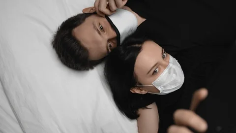 Young creative guy and girl in relationshiptaking selfie in face masks at home Stock Footage 129503810