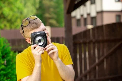 Young creative handsome man having fun outdoors, takes photo with camera Stock Photos