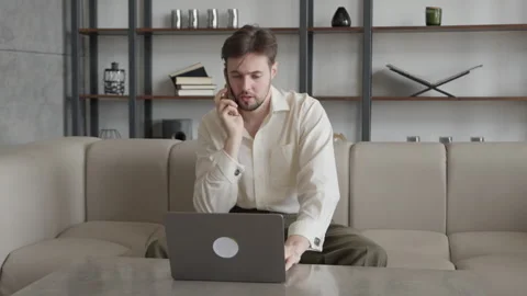 Young Creative Man with Laptop Talking on Smartphone in Office Stock Footage 295185570