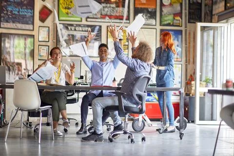Young creative people at work in the office are celebrating finished job by t Stock Photos