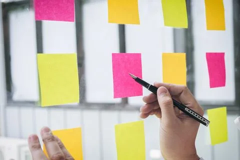 Young creative professional leader using post it notes in glass wall to wri.. Stock Photos
