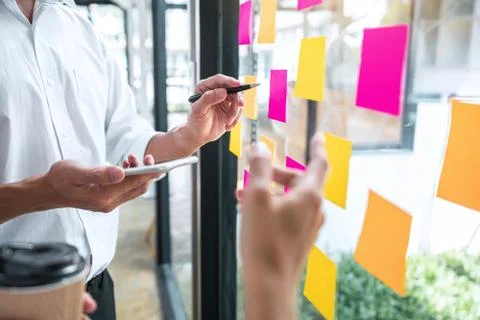 Young creative team professional using post it notes in glass wall to writing Stock Photos