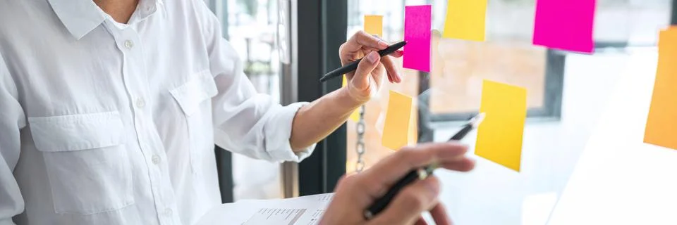 Young creative team professional using post it notes in glass wall to writing Stock Photos