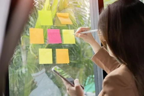 Young creative team use post it notes to share idea sticky note on glass wall Stock Photos