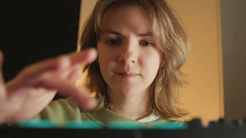 Young creator leaning over audio controller, adjusting pads and knobs with Stock-Footage 343541321