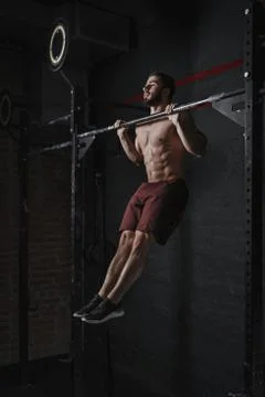 Young crossfit athlete doing pull-ups at the gym. Strong man doing functional Stock Photos