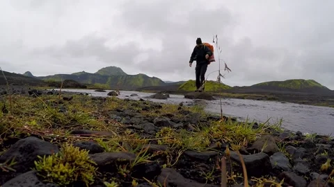 A young crossing a river in the valley on the 54 km trek from Landmannalaugar Stock Footage 130257201