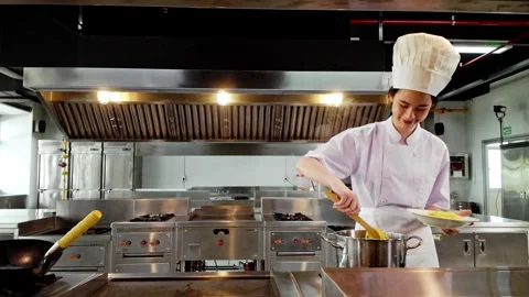 Young culinary student in a white chef uniform plating hot pasta from a pot Stock Footage 320862692