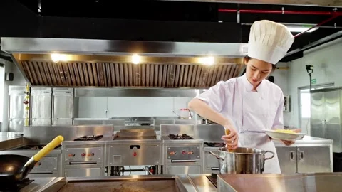 Young culinary student in a white chef uniform plating hot pasta from a pot 스톡 동영상 327122874