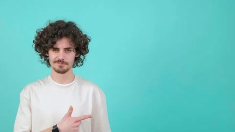 A young curly haired man is pointing to the left and showing the thumb up Stock Footage 151545939