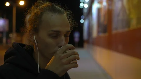 Young curly man drinks coffee on the street at night, neon light 1 Видео 96060396