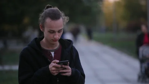 Young curly man using mobile phone  outdoors in the evening Video stock 96217182