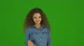 The young curly woman flirt and stand on the green background. Real time capture 4k or 4k+ Resolution