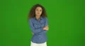 The young curly woman get an idea and stand on the green background. Real time 4k or 4k+ Resolution