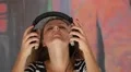 Young Curly Woman with Headphones Listening Music. HD Footage
