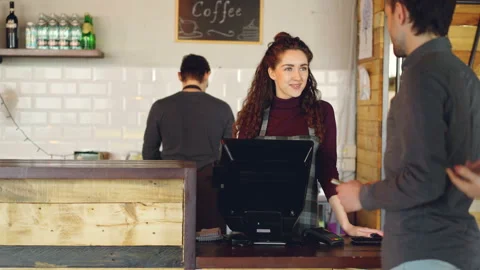 Young customers are ordering takeout coffee in coffeehouse and paying with smart Stock-Footage 89682900