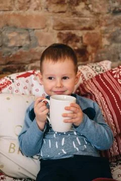 Young cute boy having hot chocolate in bed with a blanket Stock Photos