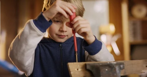 Young cute boy is screwing a screw into wood in the workbench Stock Footage 85809254